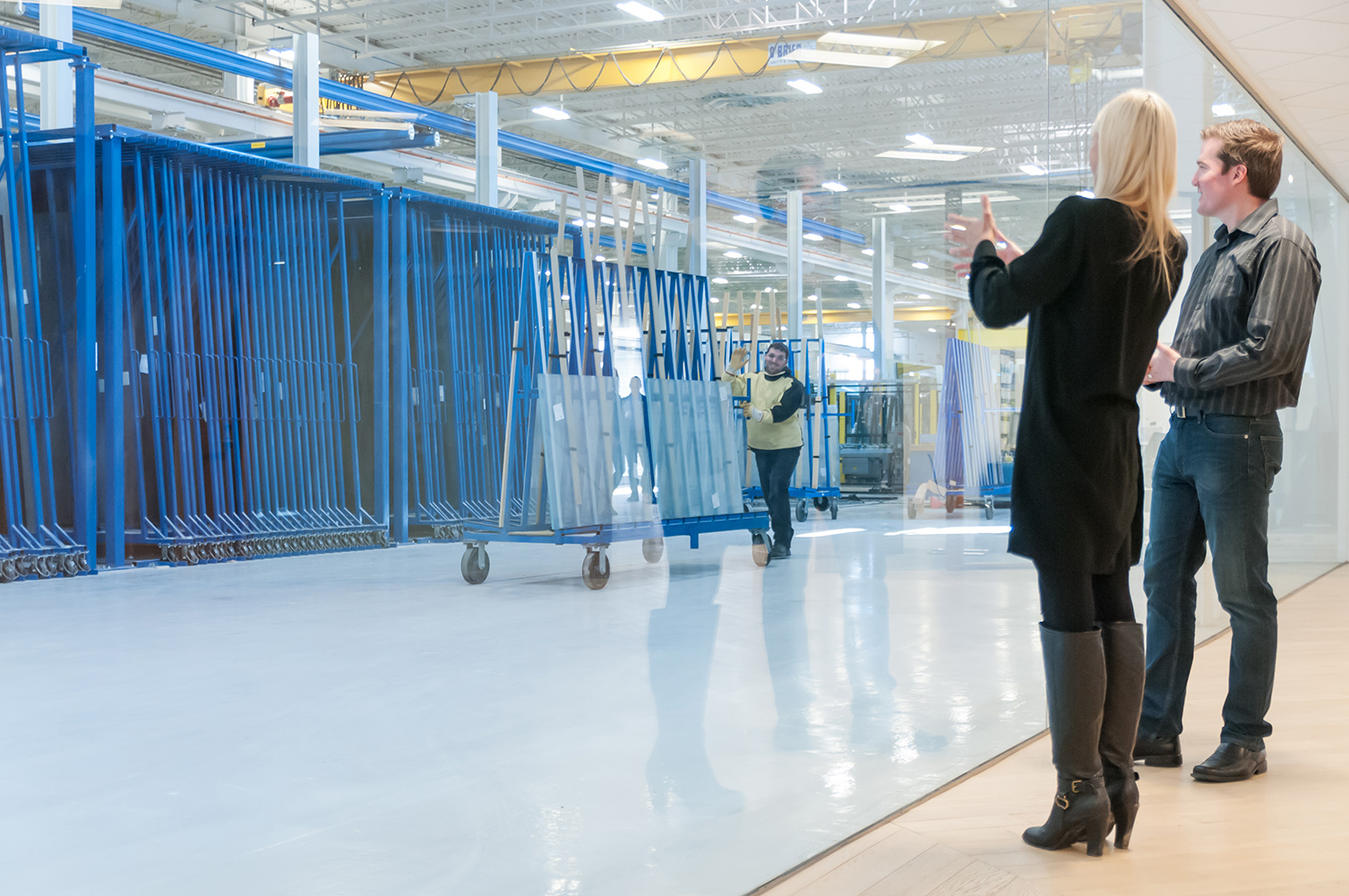 AGNORA staff member pushing an A-frame of glass as two office employees wave and look on.