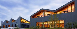 Exterior shot of WMS Boathouse at Clark Park, Chicago featuring Interior shot of rowing team training in gym facility in front of Oversized, daylighting insulated glass units.