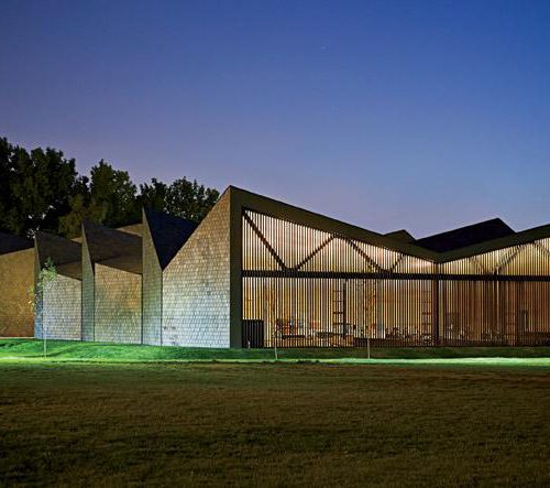 Exterior shot of WMS Boathouse at Clark Park, Chicago featuring Interior shot of rowing team training in gym facility in front of Oversized, daylighting insulated glass units.