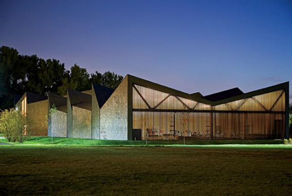 Exterior shot of WMS Boathouse at Clark Park, Chicago featuring Interior shot of rowing team training in gym facility in front of Oversized, daylighting insulated glass units.