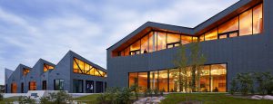 Exterior shot of WMS Boathouse at Clark Park, Chicago featuring Interior shot of rowing team training in gym facility in front of Oversized, daylighting insulated glass units.