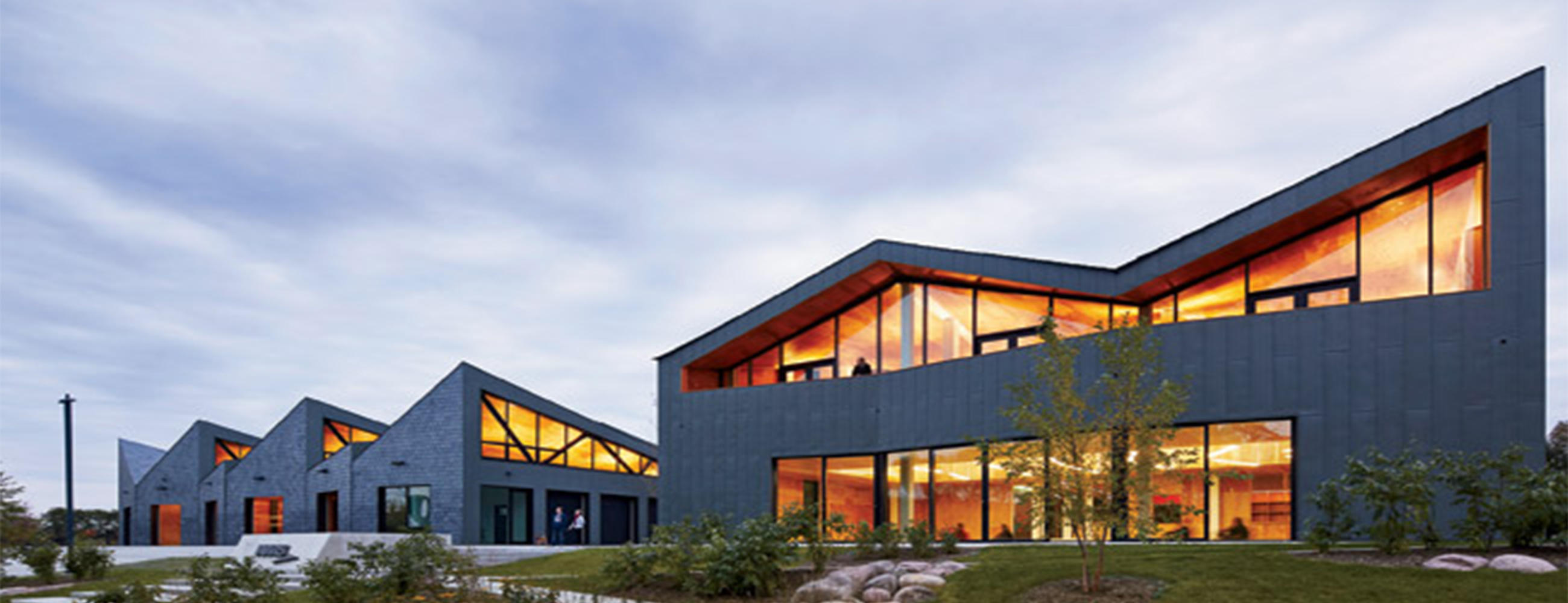 Exterior shot of WMS Boathouse at Clark Park, Chicago featuring Interior shot of rowing team training in gym facility in front of Oversized, daylighting insulated glass units.