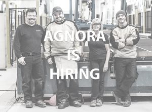 4 employees stand against equipment at AGNORA