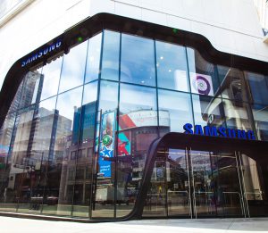 Exterior street view of all-glass façade for Samsung consists of oversized/jumbo, insulated, Low-E, glass units with complex, compound curves fabricated by AGNORA