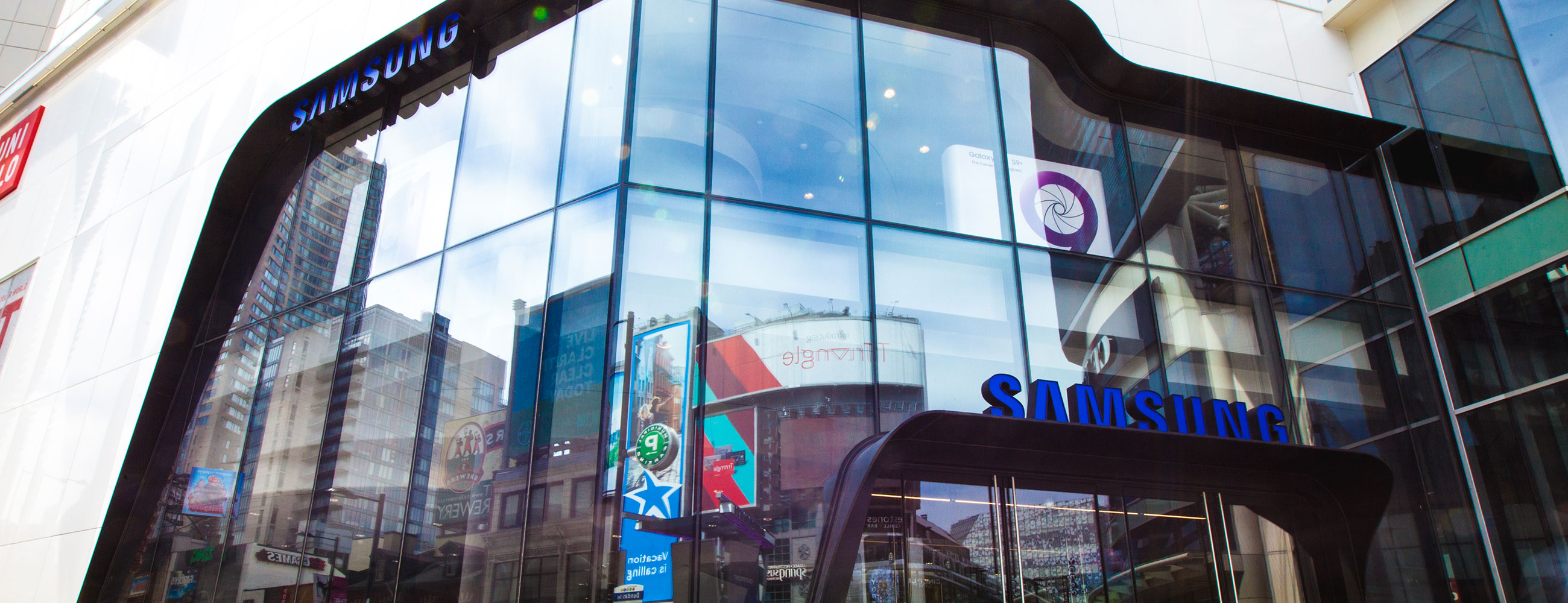 Exterior street view of all-glass façade for Samsung consists of oversized/jumbo, insulated, Low-E, glass units with complex, compound curves fabricated by AGNORA